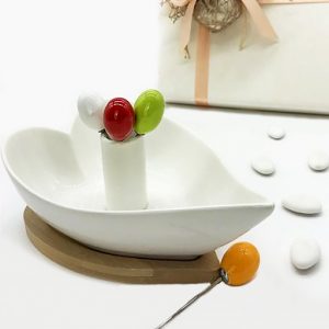 Ciotola ceramica bianca a forma di cuore, su supporto in legno di bamboo, fornite di 4 spadini in acciaio con pomello colorato, inseriti nell'apposito spazio al centro della ciotolina a forma di cuore
