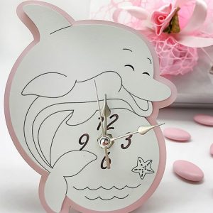 Bomboniera orologio Delfino rosa realizzato in legno. Composto da una base rosa, raffigurato su legno bianco, con dettagli incisi ed altri intagliati. Lancette in silver e supporto retrostante per l'utilizzo come orologio da appoggio.