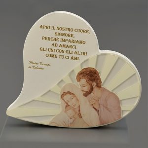 Icona Sacra Famiglia realizzata in legno da tavolo a forma di cuore, di colore bianco con inserto in plexiglass su cui è raffigurata la Sacra Famiglia e che riportano in calce una frase incisa di Madre Teresa di Calcutta. 