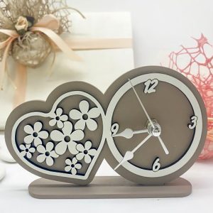 Orologio cuore da tavolo, presenta un design raffinato con una struttura e un sostegno in legno color tortora, arricchiti da un effetto doppiato con sovrapposizione in rilievo in tonalità bianco ottico