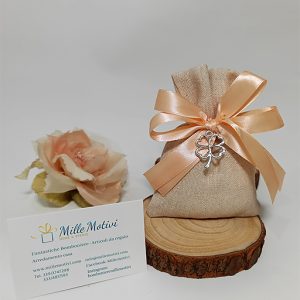 Sacchetto beige con applicazione ciondolo quadrifoglio portafortuna. Scegli di ricevere il sacchettino completo di confetti.