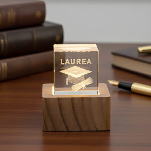 Cubo laurea in cristallo con base in legno. La bomboniera è realizzata in vetro, alla base una luce led rende atmosfera magica